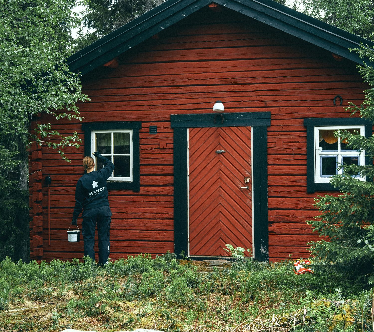 Painter coating the exterior of a timber home